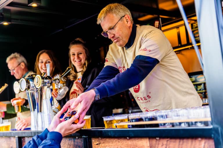Vrijwilligers tappen bier aan de bar van KOZ Festival