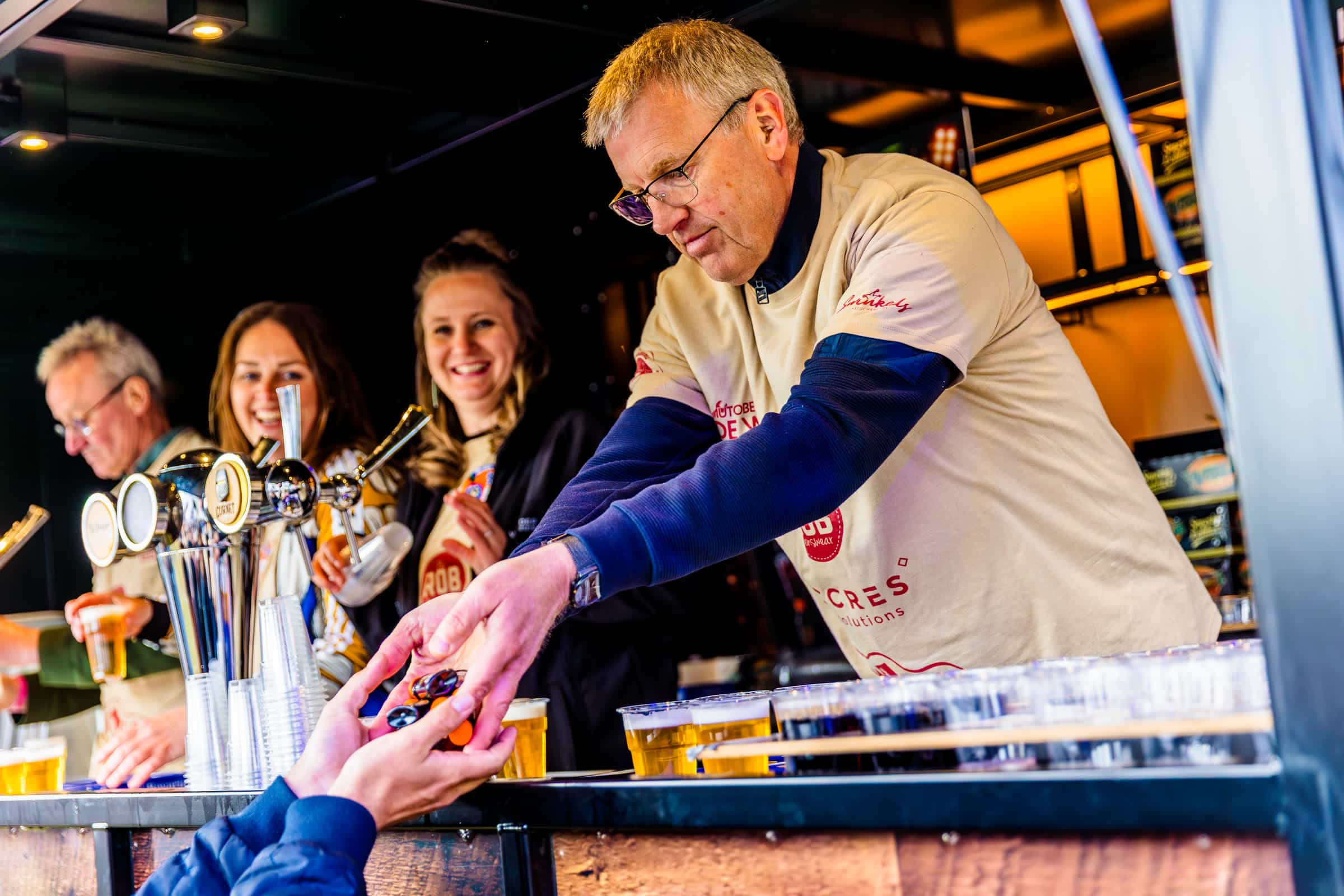 Vrijwilligers tappen bier aan de bar van KOZ Festival