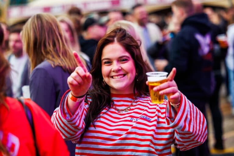 Lachende bezoeker proost met een biertje op KOZ Festival